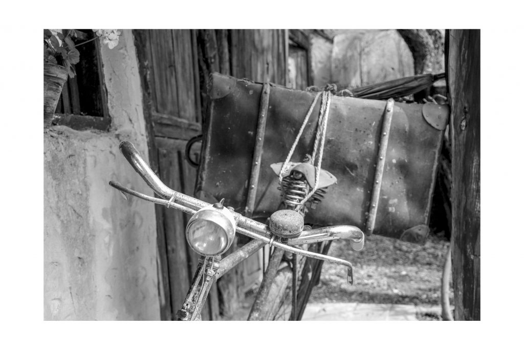 Bicicleta antigua oxidada con una maleta en el portaequipajes atada con una cuerda